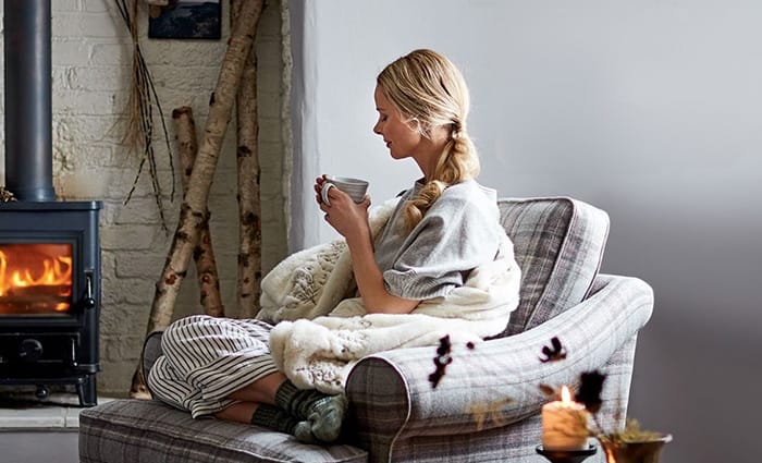 Colț hygge cu lumânări parfumate, pătură pufoasă și decor cozy